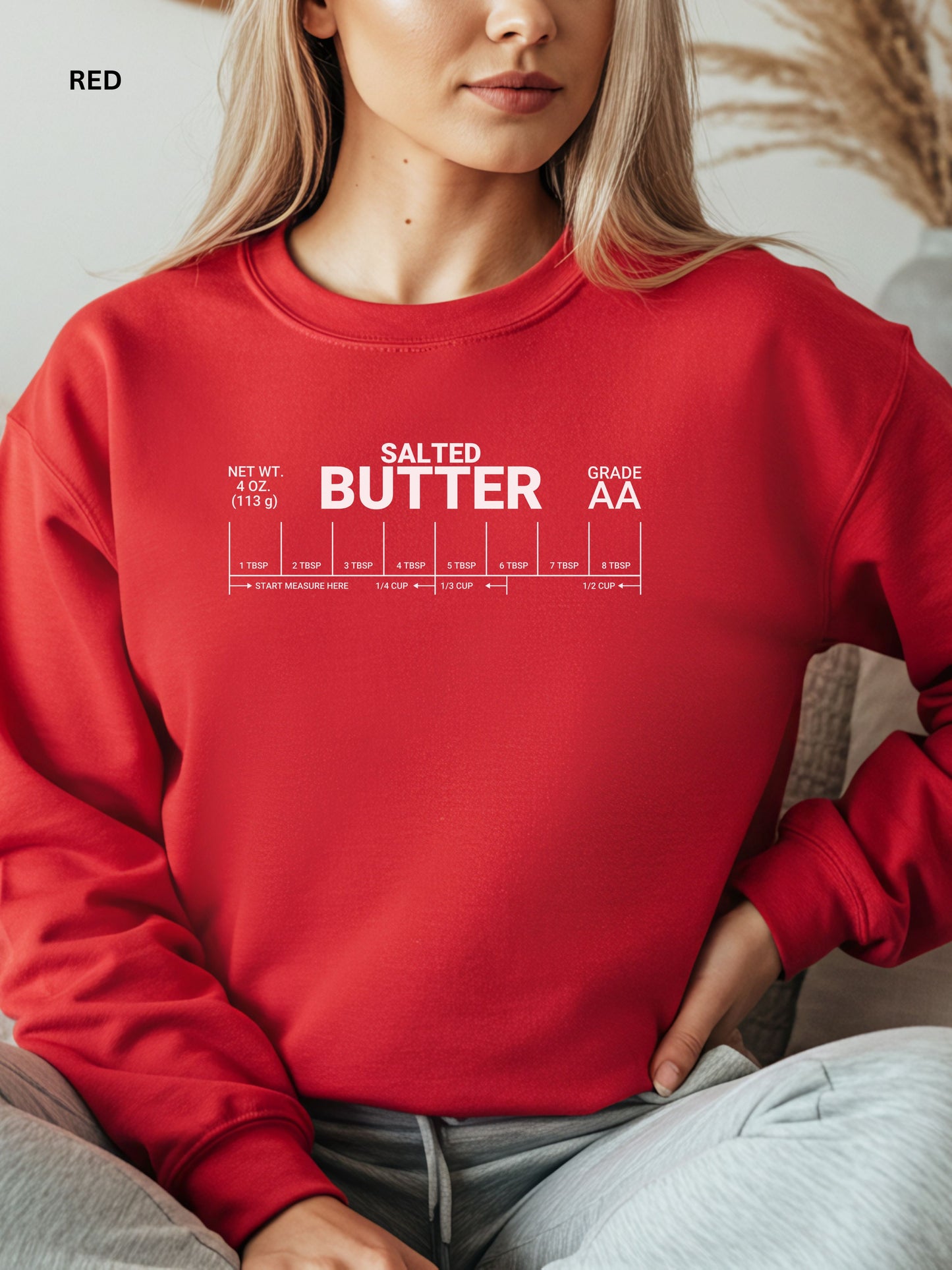 Person wearing a red sweatshirt with 'Salted Butter Grade AA' text design.