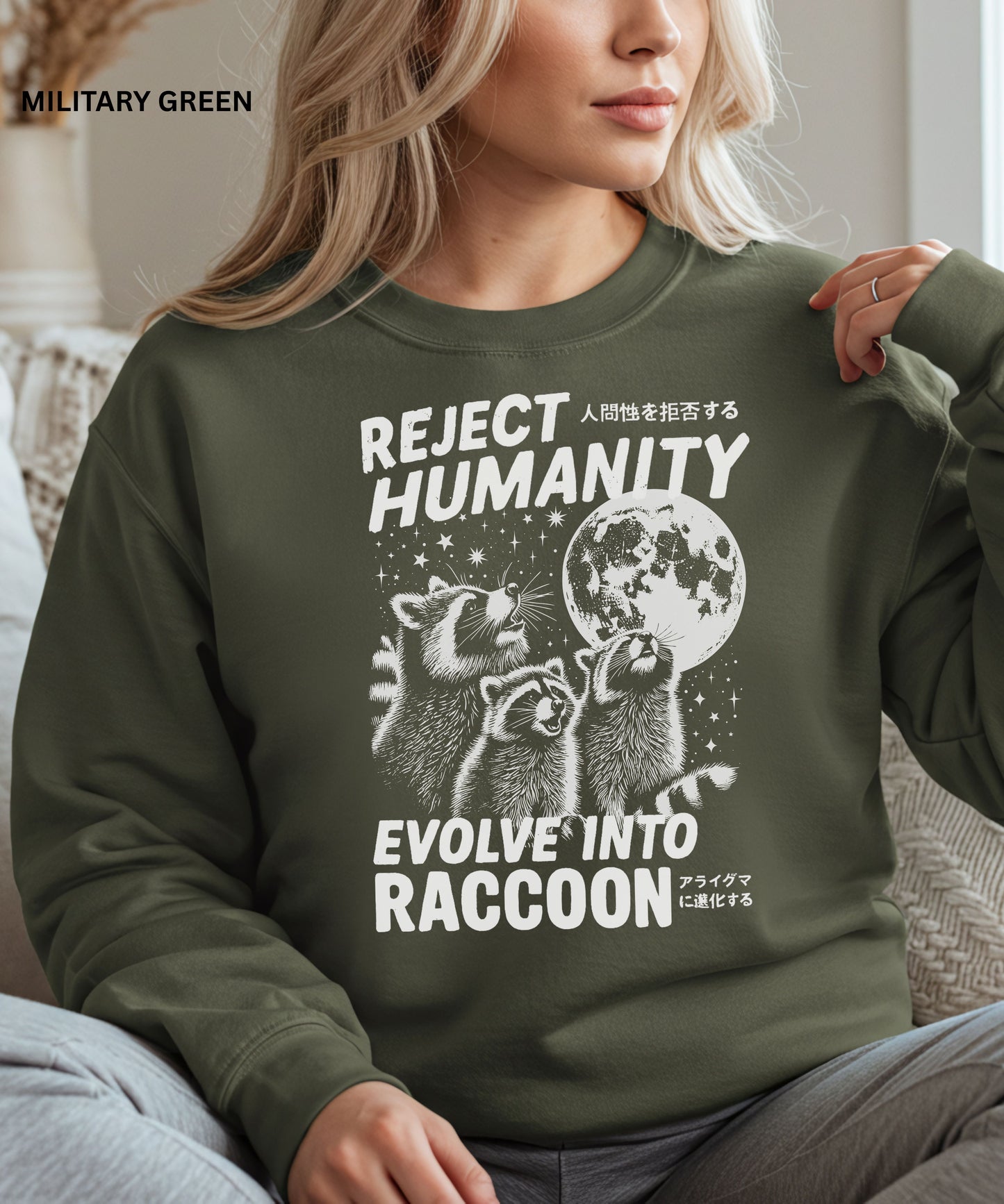 Person wearing a military green colored sweatshirt with a graphic design that says "reject humanity evolve into racoon" sitting on a couch.
