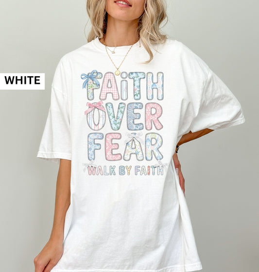 White t-shirt with 'Faith Over Fear' text worn by a model on a gray background