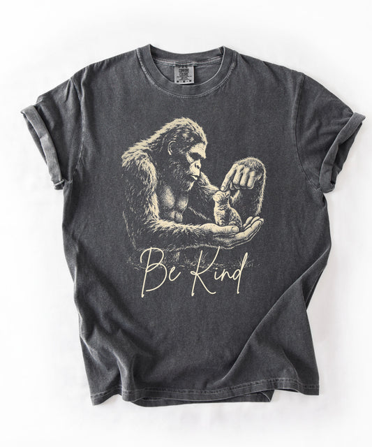 Bigfoot booping a cat on the nose graphic tee in Pepper — "Be Kind" garment-dyed heavyweight shirt