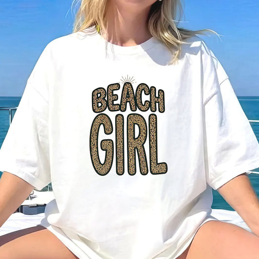 Person wearing a white t-shirt with 'Beach Girl' text in front of a blue ocean background