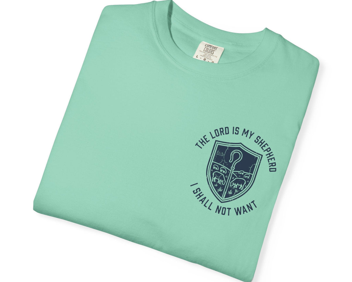 A folded Island Reef t-shirt with a dark navy blue graphic on the front. The graphic features a shepherd's crook inside a shield, surrounded by the text 'THE LORD IS MY SHEPHERD I SHALL NOT WANT'.