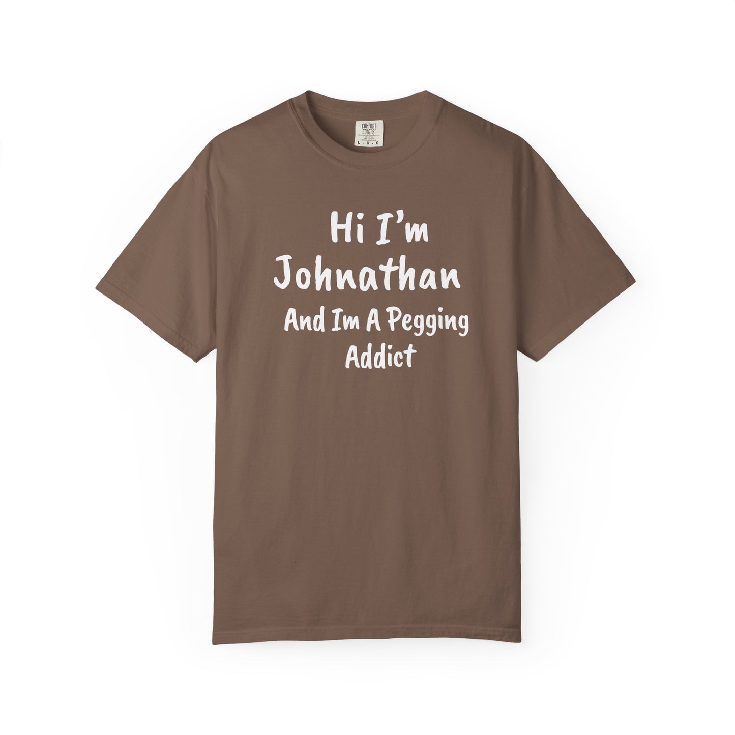 Espresso garment-dyed heavyweight t-shirt with personalized 'Hi I'm [Name] And I'm A Pegging Addict' graphic in handwritten-style font, centered on chest
