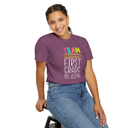 Person wearing a berry colored t shirt with  'Team First Grade' on a white background