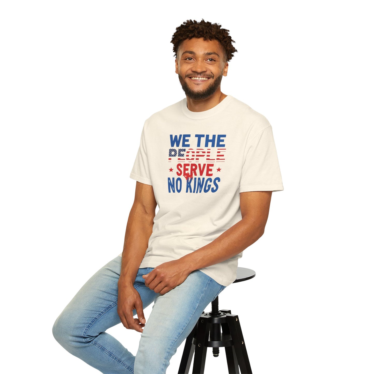 Man wearing a t-shirt with 'We the People Serve No Kings' text, sitting on a stool against a white background