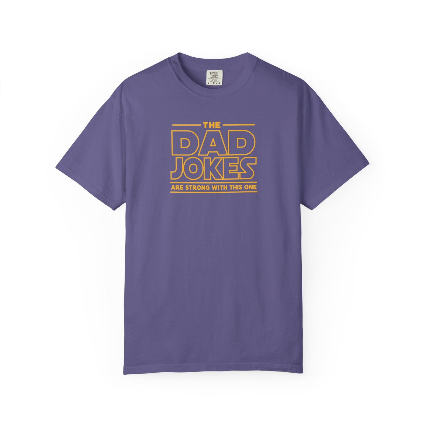 a grape t-shirt with yellow text 'The Dad Jokes Are Strong With This One' in front of a blurred background.