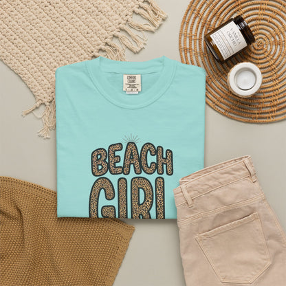 Folded chalky mint t-shirt with 'Beach Girl' text on a neutral surface with accessories.