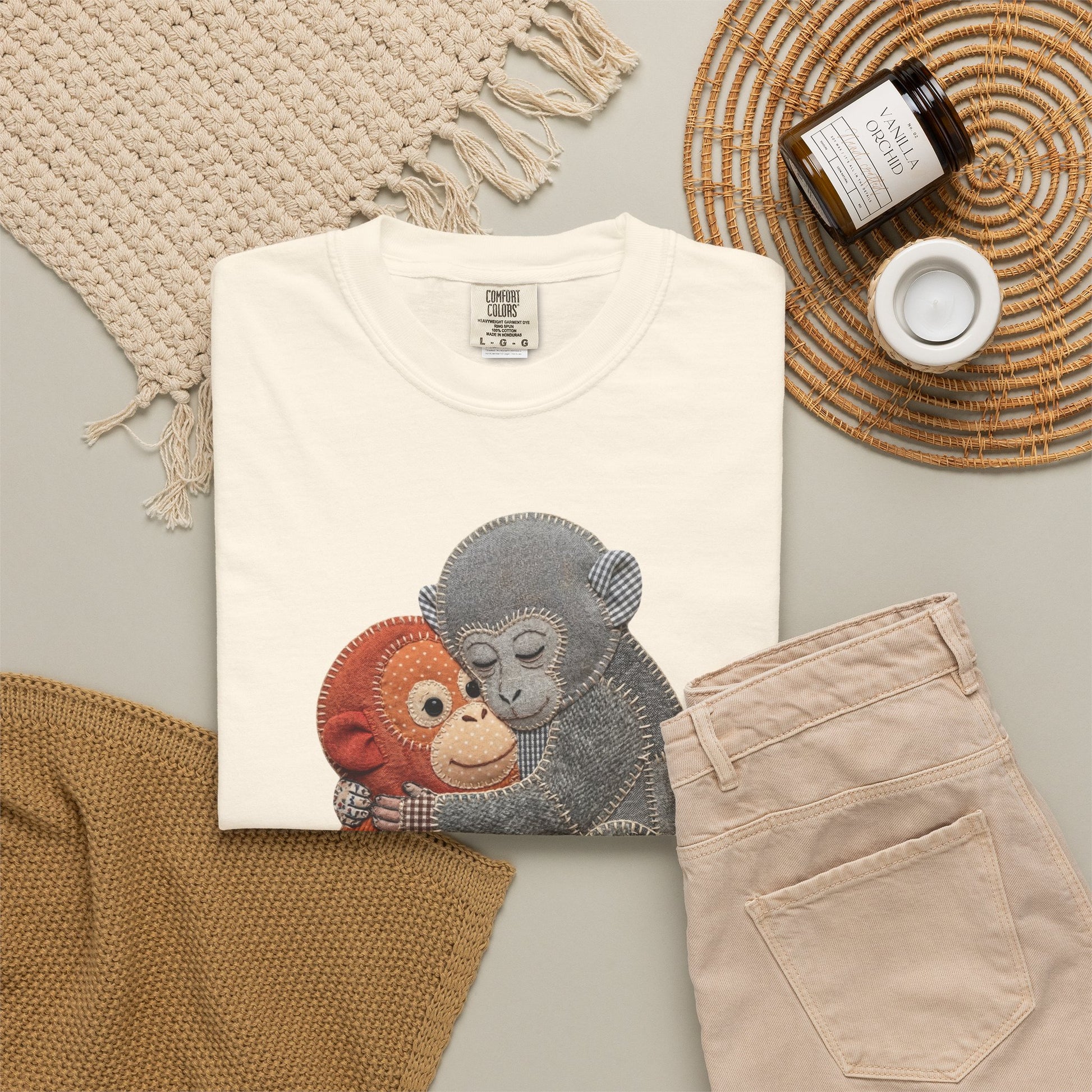 ivory t-shirt with monkey design, beige pants, and decorative items on a light gray surface