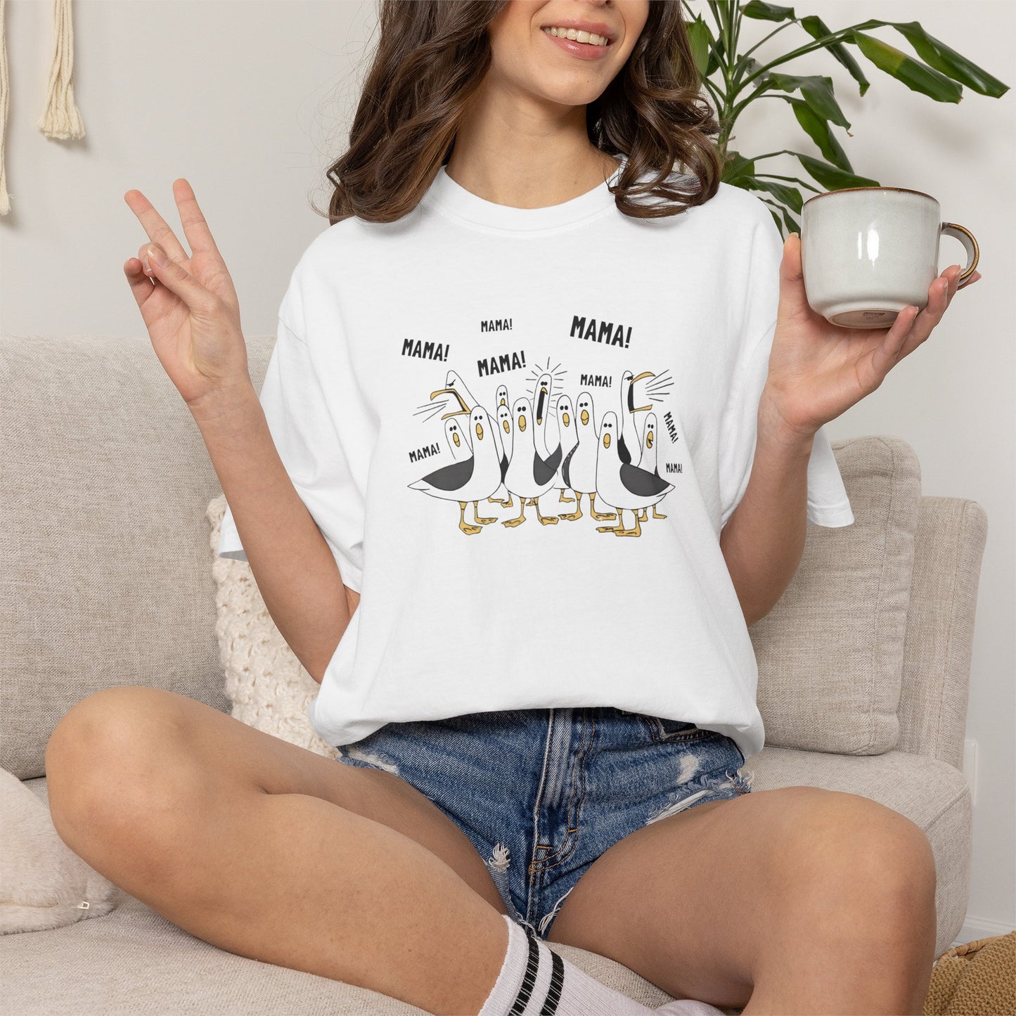 White t-shirt with cartoon penguins screaming "Mama"  design and text worn by a person.