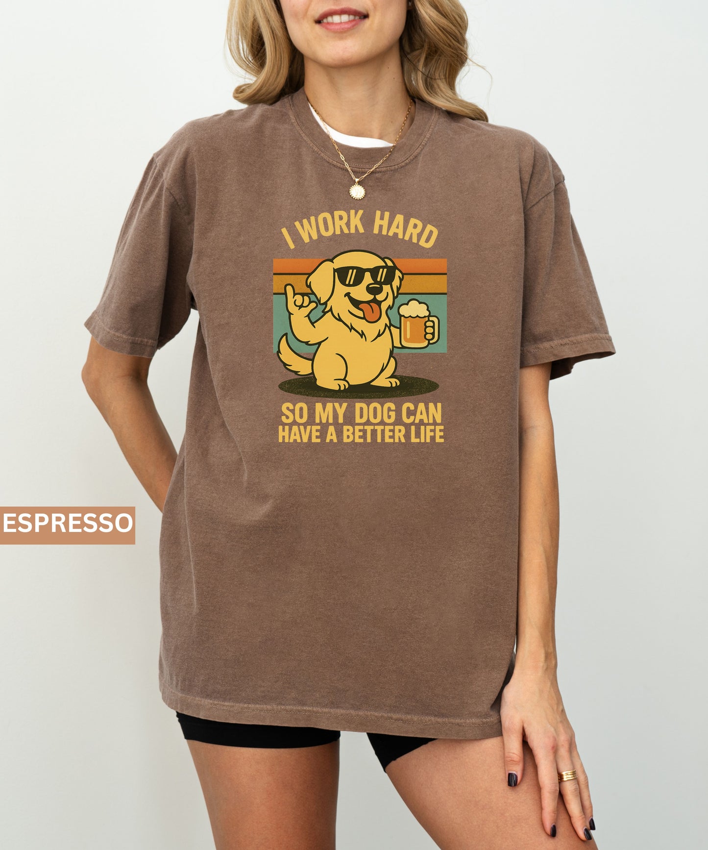 Person wearing an espresso t-shirt with a graphic of a dog and text that says "i work hard so my dog can have a better life, set indoors.