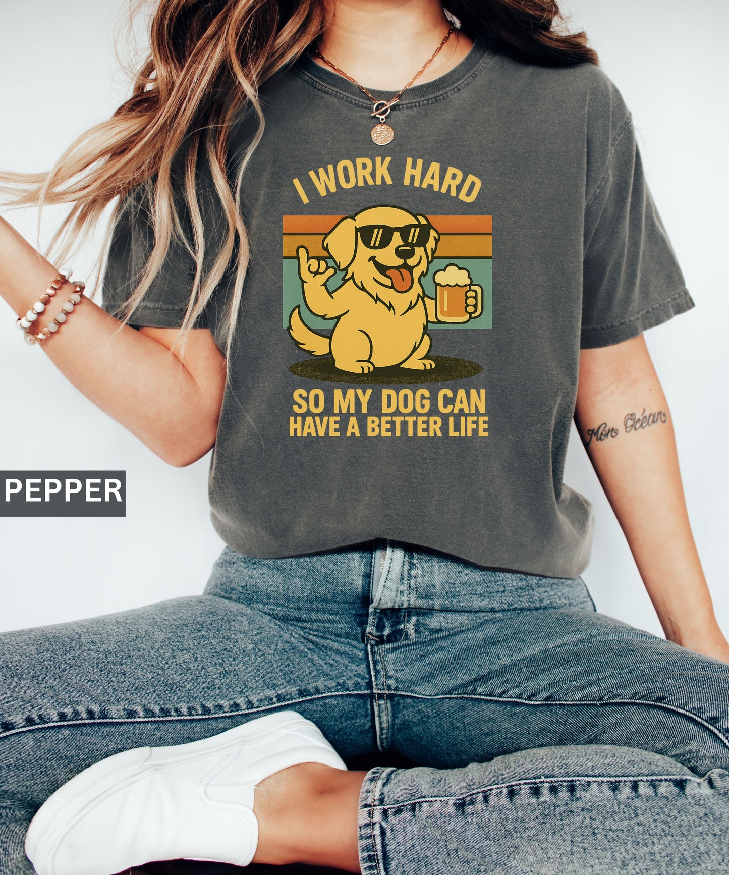 Person wearing a pepper t-shirt with a graphic of a dog and text that says "i work hard so my dog can have a better life, set indoors.
