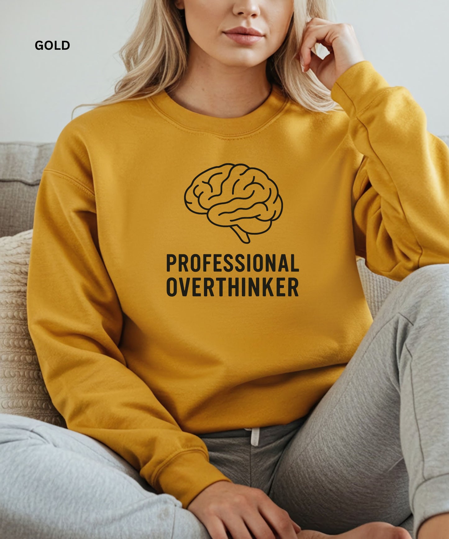 Person wearing a gold sweatshirt with a brain graphic and 'Professional Overthinker' text, sitting on a couch.

