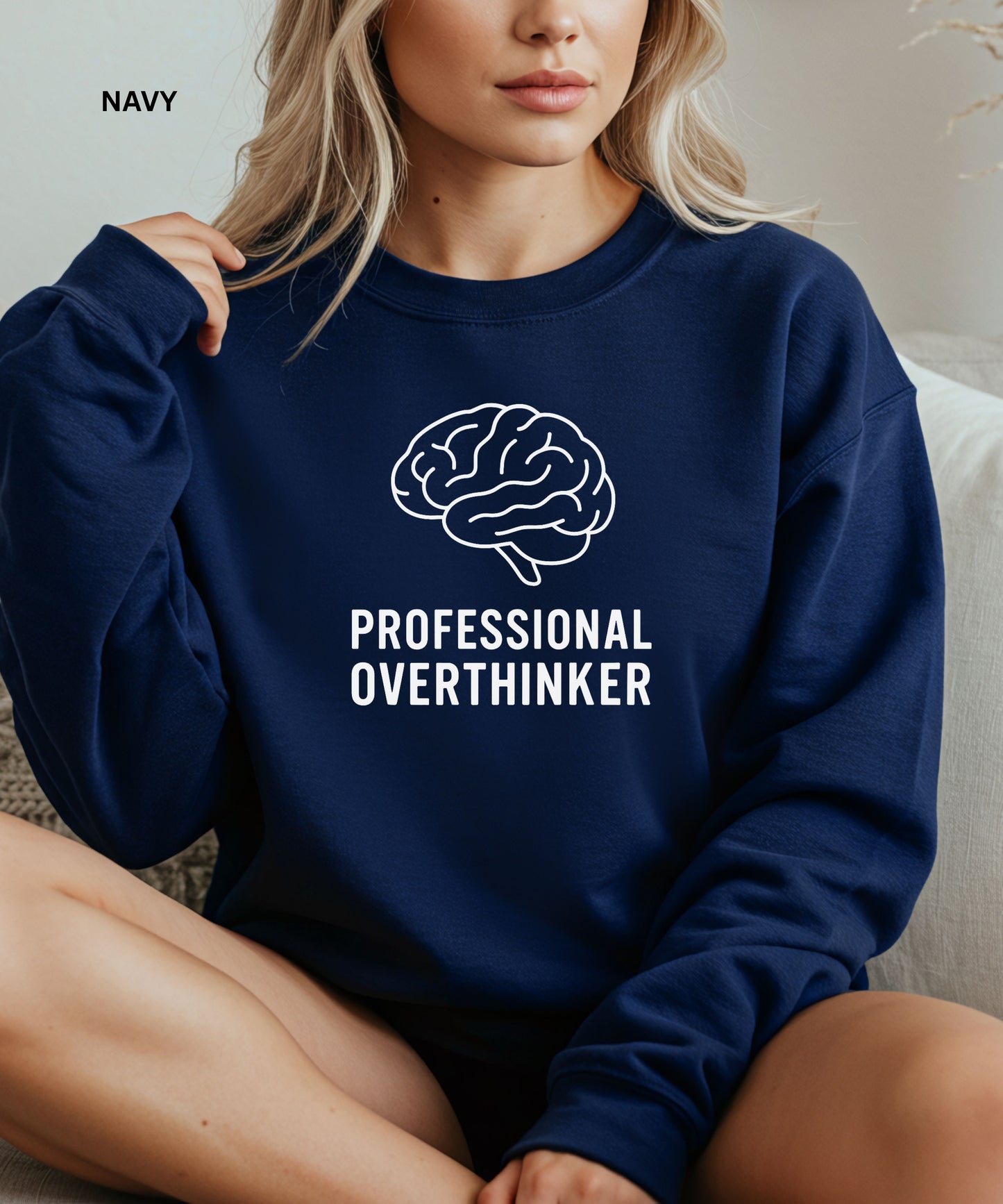 Navy sweatshirt with brain graphic and 'Professional Overthinker' text worn by a person.