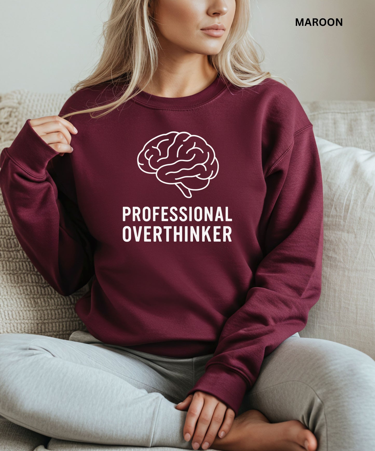 Person wearing a maroon sweatshirt with a brain graphic and 'Professional Overthinker' text, sitting on a couch.