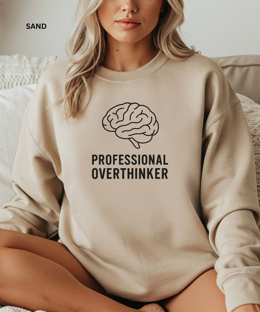 Person wearing a sand sweatshirt with a brain graphic and text 'Professional Overthinker' on a neutral background.