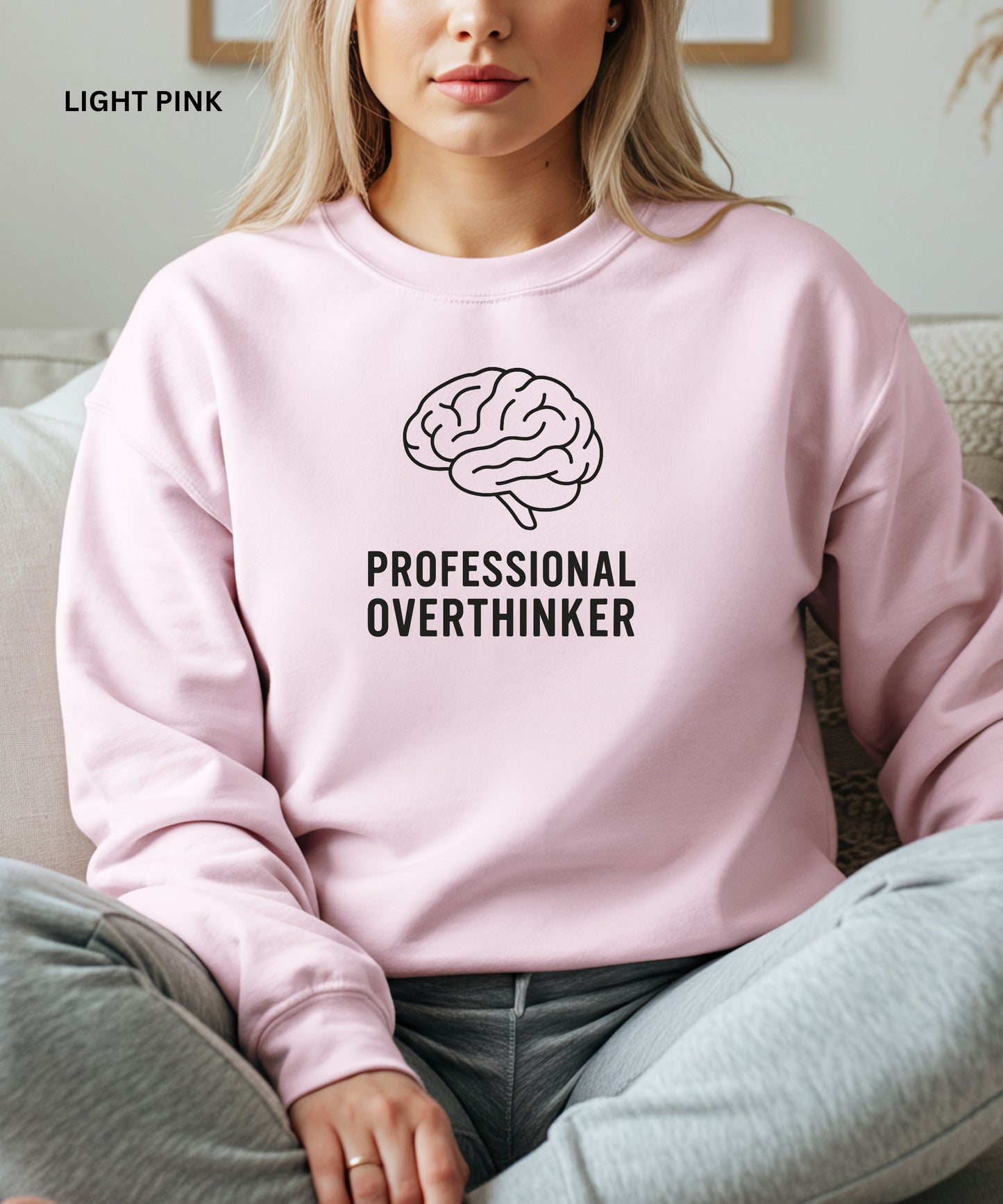 Person wearing a light pink sweatshirt with a brain graphic and text 'Professional Overthinker'.