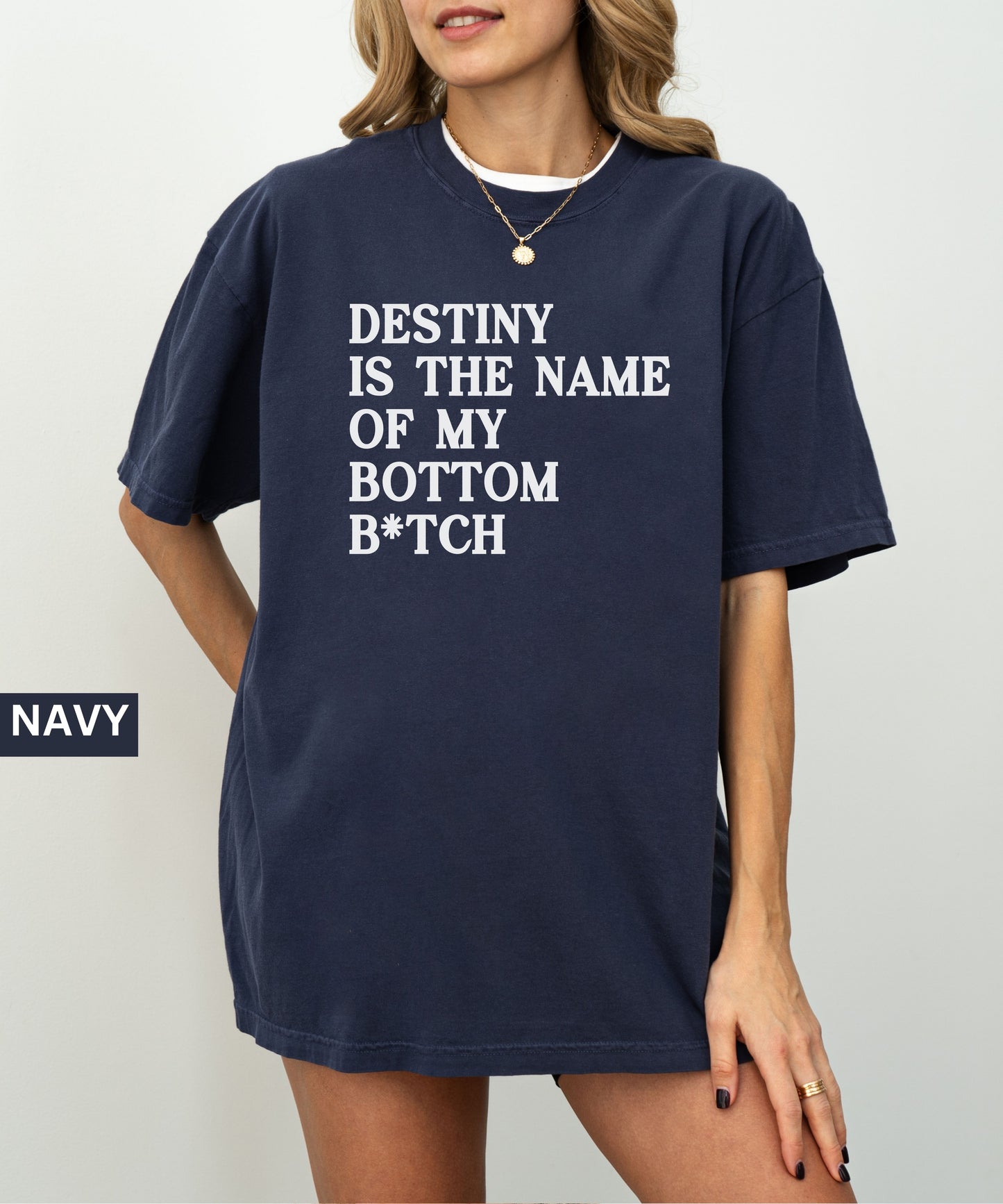 Person wearing a navy t-shirt with text 'Destiny is the name of my bottom B*tch' on a plain background.