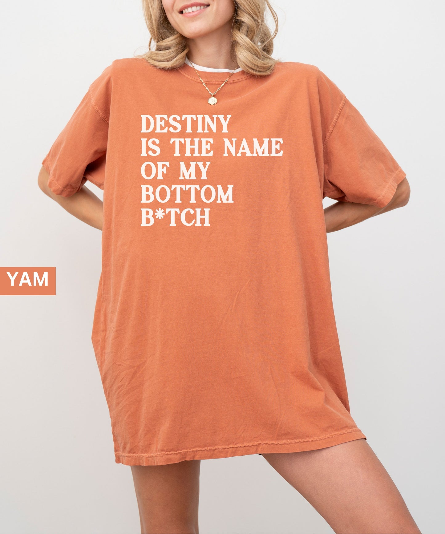Person wearing an orange  t-shirt with text 'Destiny is the name of my bottom B*tch' on a plain background.