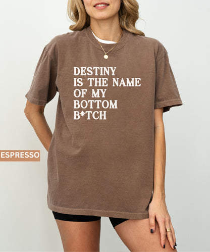 Person wearing a espresso t-shirt with text 'Destiny is the name of my bottom B*tch' on a plain background.