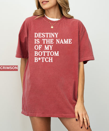 Person wearing a crimson t-shirt with text 'Destiny is the name of my bottom B*tch' on a plain background.