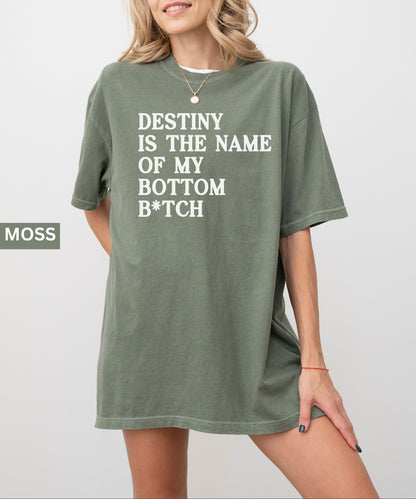 Person wearing a moss t-shirt with text 'Destiny is the name of my bottom B*tch' on a plain background.