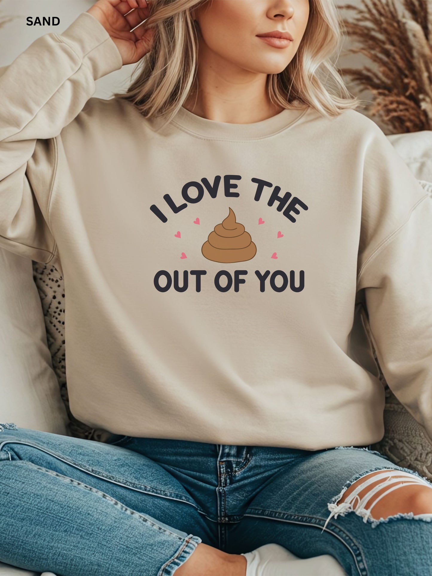 Person wearing a sand  sweatshirt with a humorous design that says"i love the shit out of you", sitting on a couch.