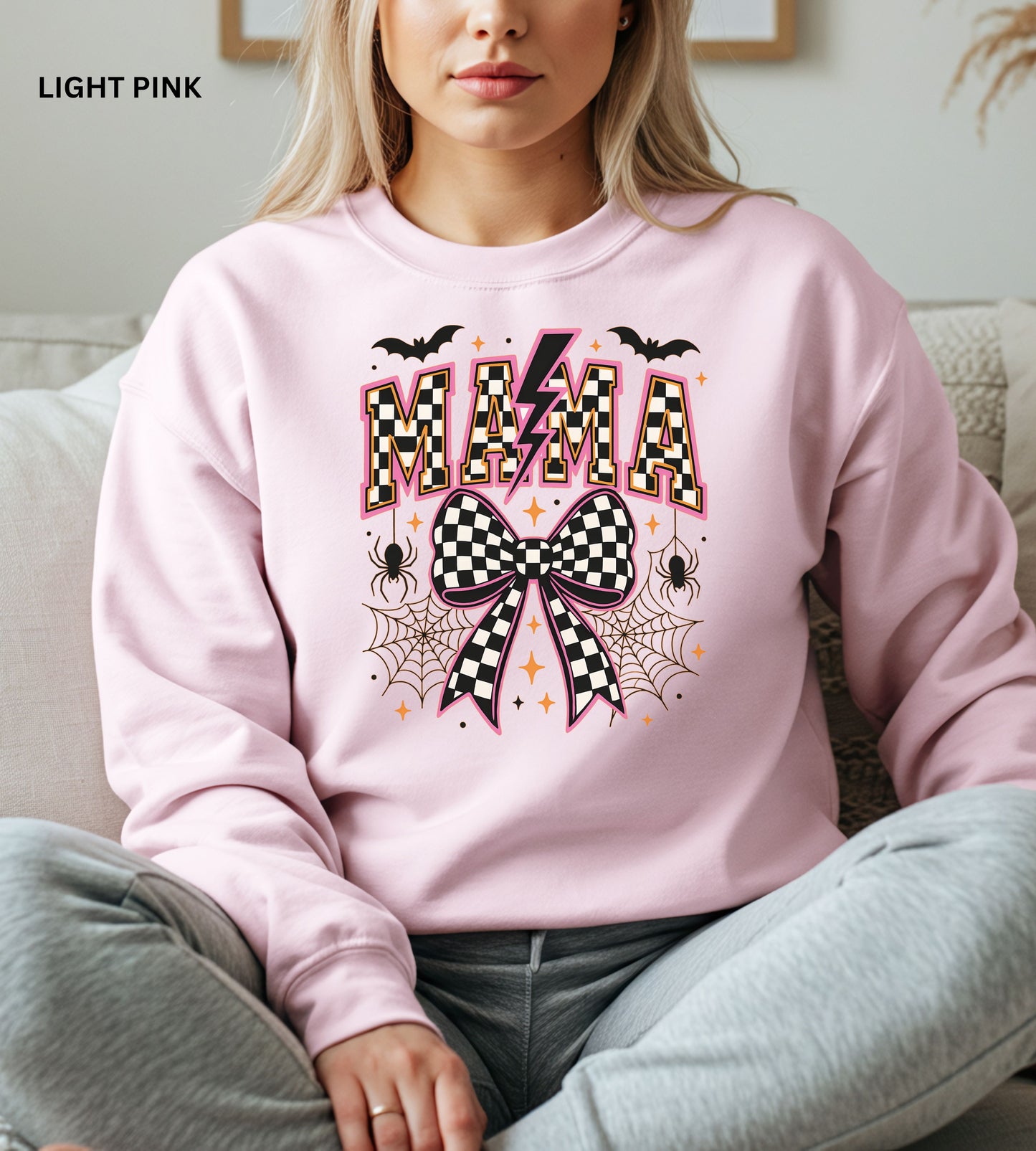 Person wearing a light pink sweatshirt with 'MAMA' and Halloween-themed design.