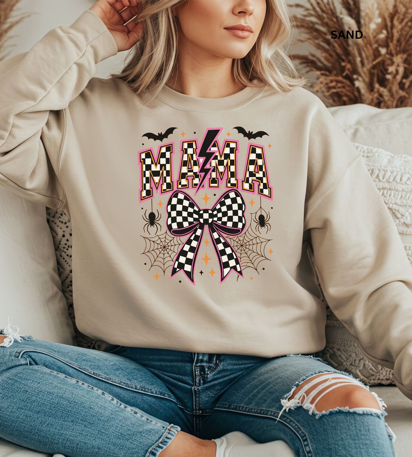 Person wearing a sand sweatshirt with Halloween-themed design, sitting on a textured surface.