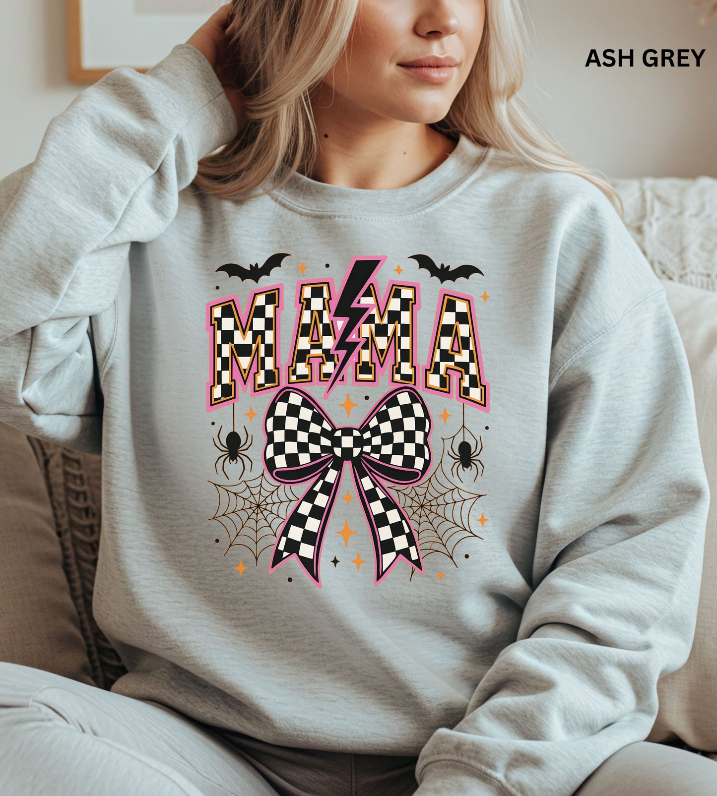 Person wearing an ash grey sweatshirt with Halloween-themed design, including the word 'MAMA' and checkered patterns.