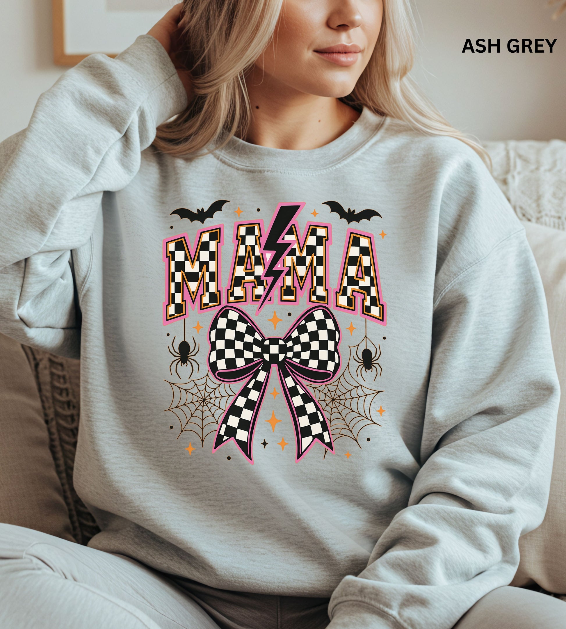 Person wearing an ash grey sweatshirt with Halloween-themed design, including the word 'MAMA' and checkered patterns.