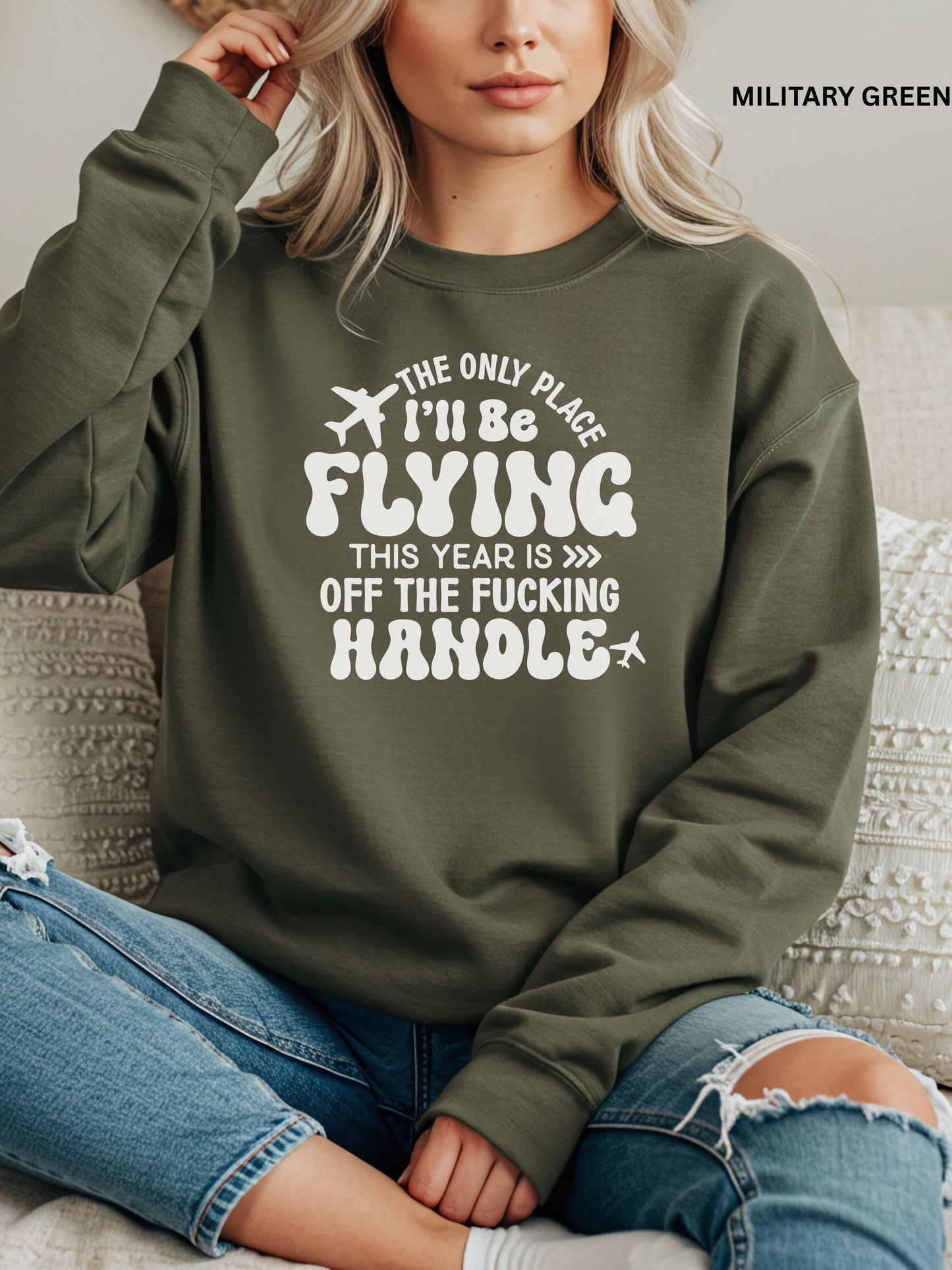 Person wearing a military green sweatshirt with a humorous text design that says "the only place ill be flying is off the fucking handle, sitting on a couch.