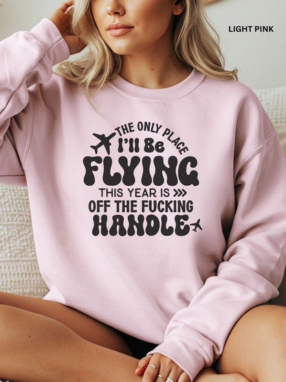 Person wearing a light pink sweatshirt with a humorous text design that says "the only place ill be flying is off the fucking handle, sitting on a couch.