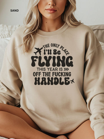 Person wearing a sand sweatshirt with a humorous text design that says "the only place ill be flying is off the fucking handle, sitting on a couch.