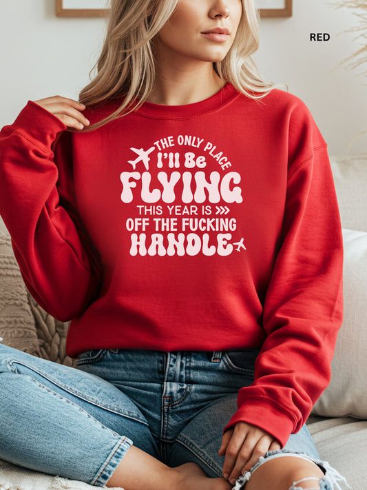 Person wearing a red sweatshirt with a humorous text design that says "the only place ill be flying is off the fucking handle, sitting on a couch.