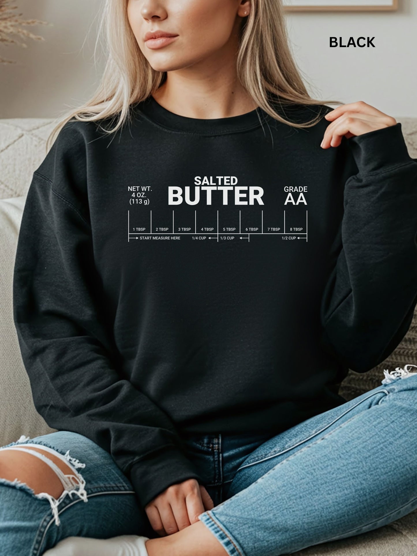 Person wearing a black sweatshirt with 'SALTED BUTTER' text, sitting on a couch.