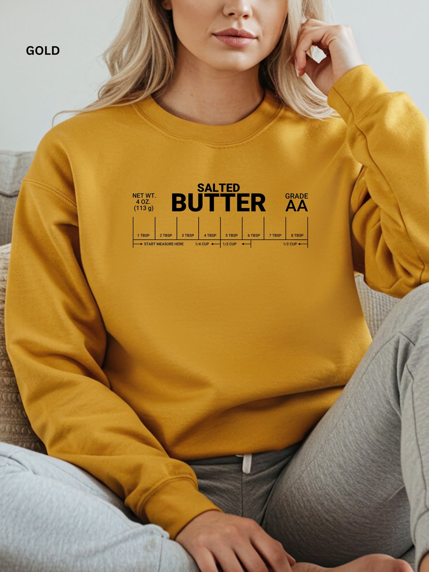 Person wearing a gold sweatshirt with 'Salted Butter' text design.