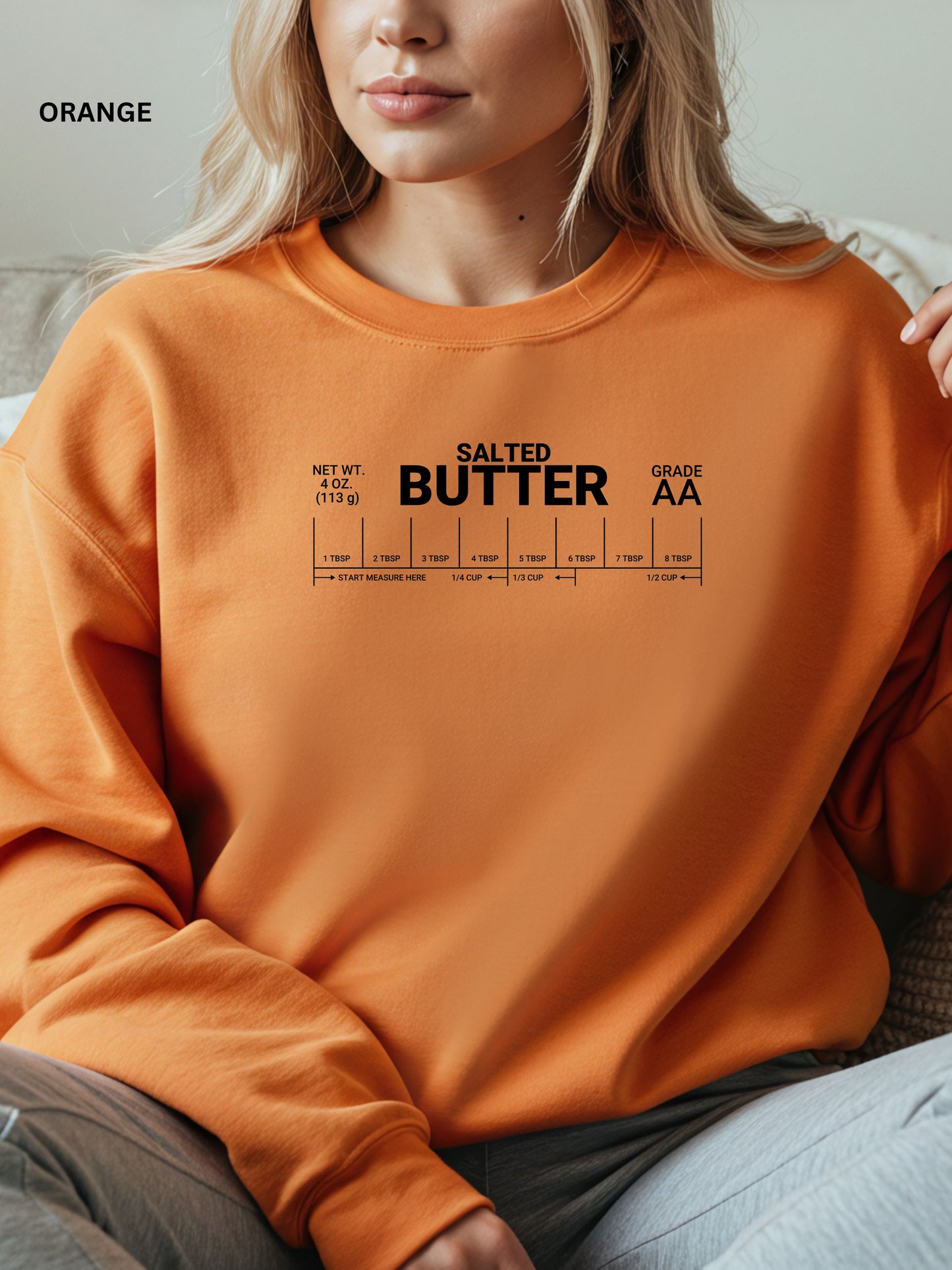 Person wearing an orange sweatshirt with 'Salted Butter Grade AA' text and measurement scale.