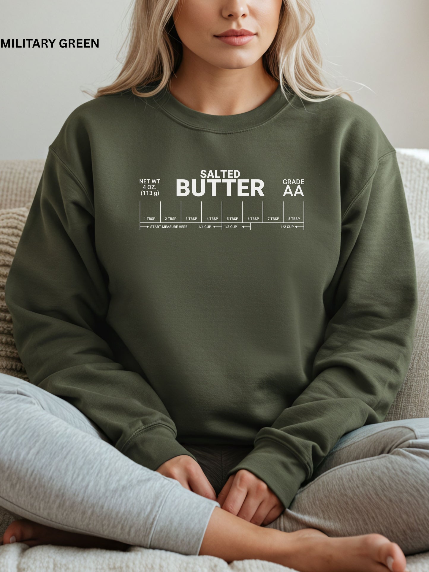 Person wearing a military green sweatshirt with 'Salted Butter' text sitting on a couch.