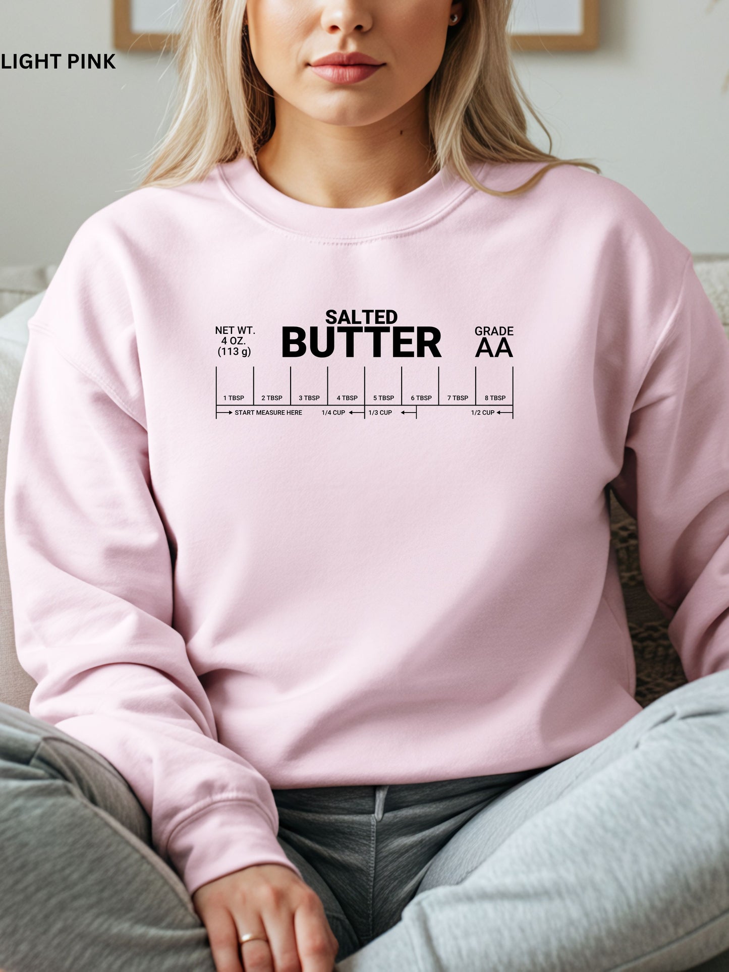 Person wearing a pink sweatshirt with 'Salted Butter' text and measurement details.