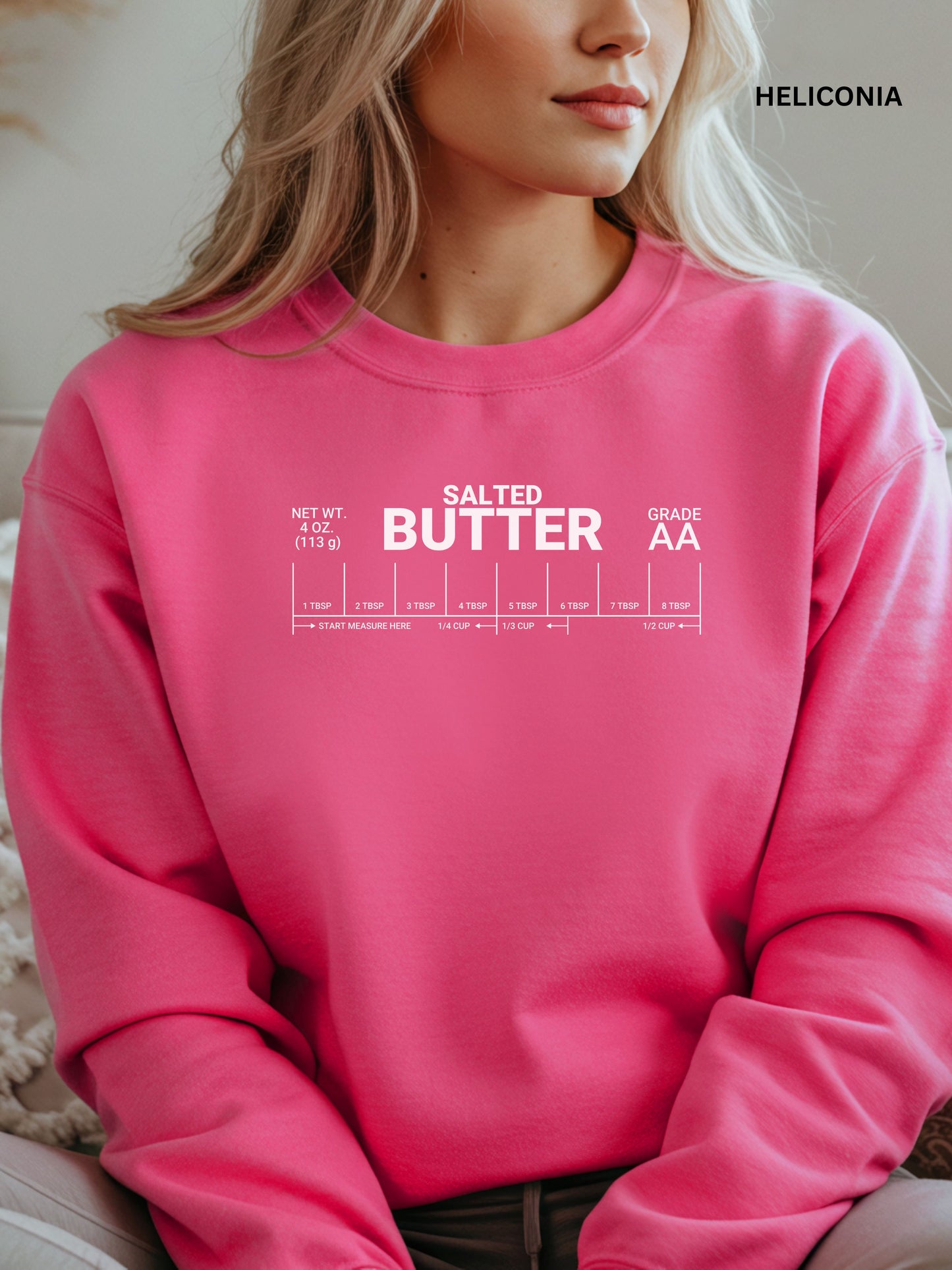 Person wearing a heliconia sweatshirt with 'SALTED BUTTER' text, sitting indoors.