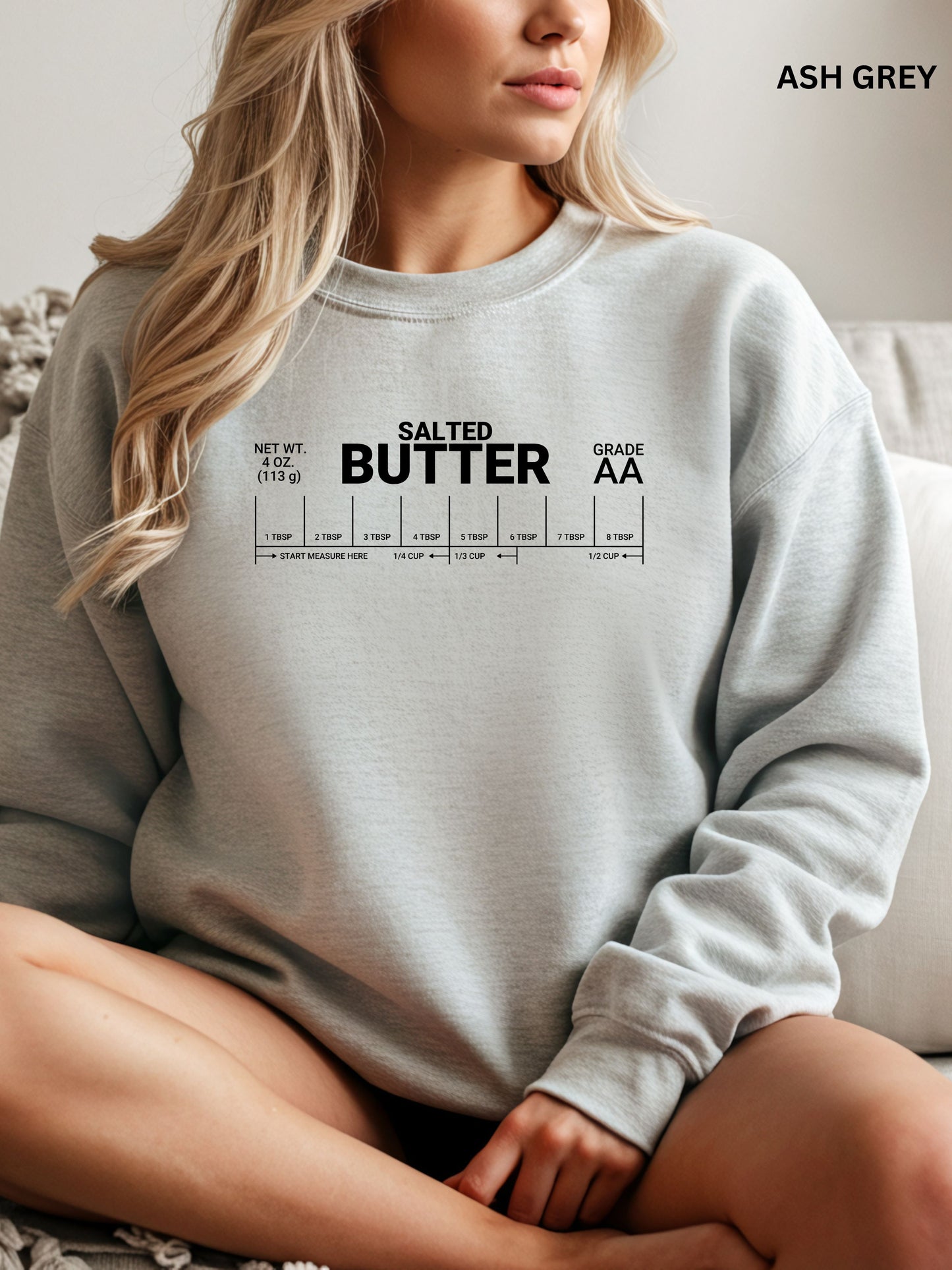 Person wearing a light gray sweatshirt with 'Salted Butter' text design.