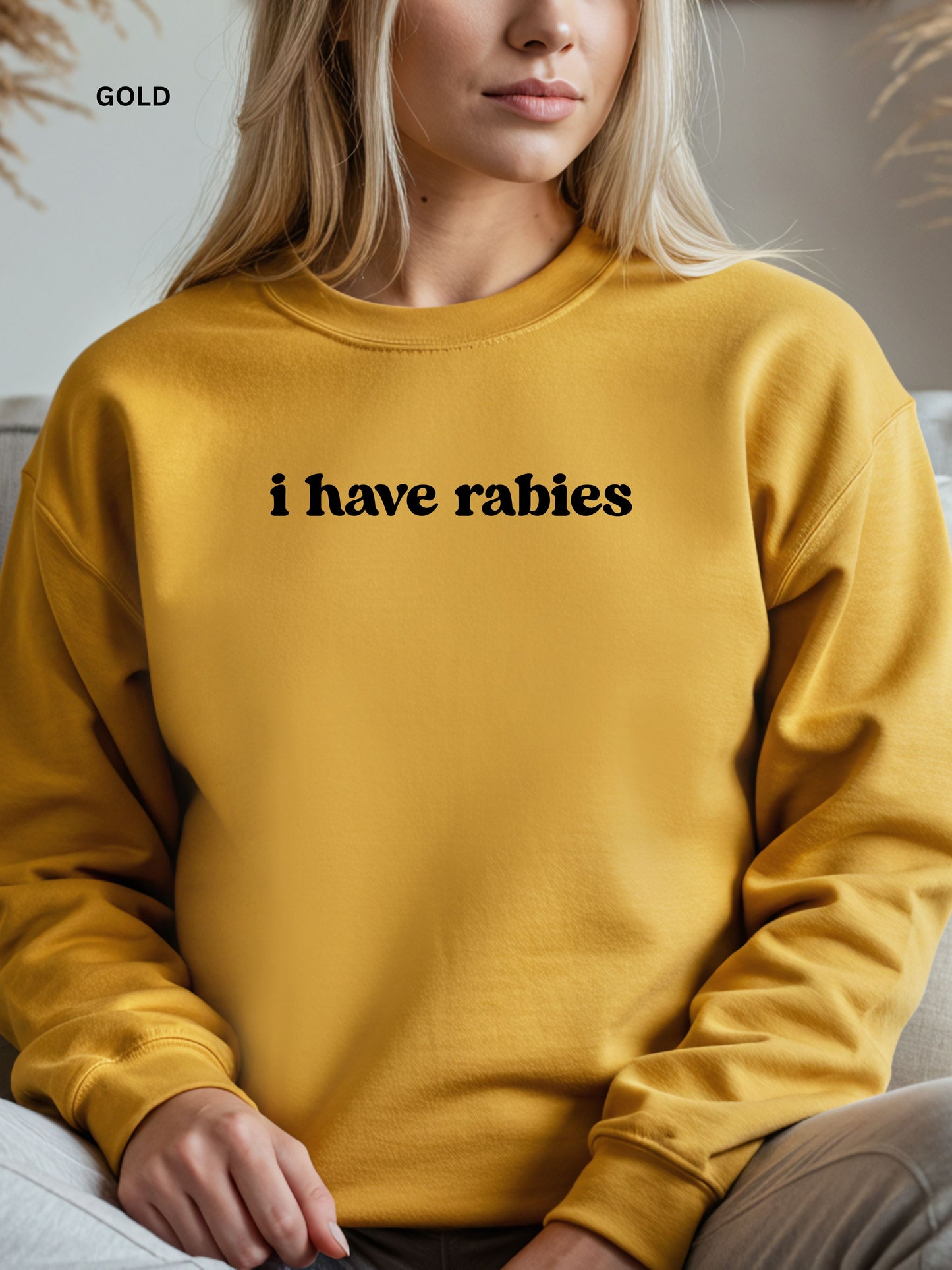 Person wearing a gold  sweatshirt with 'i have rabies' text.
