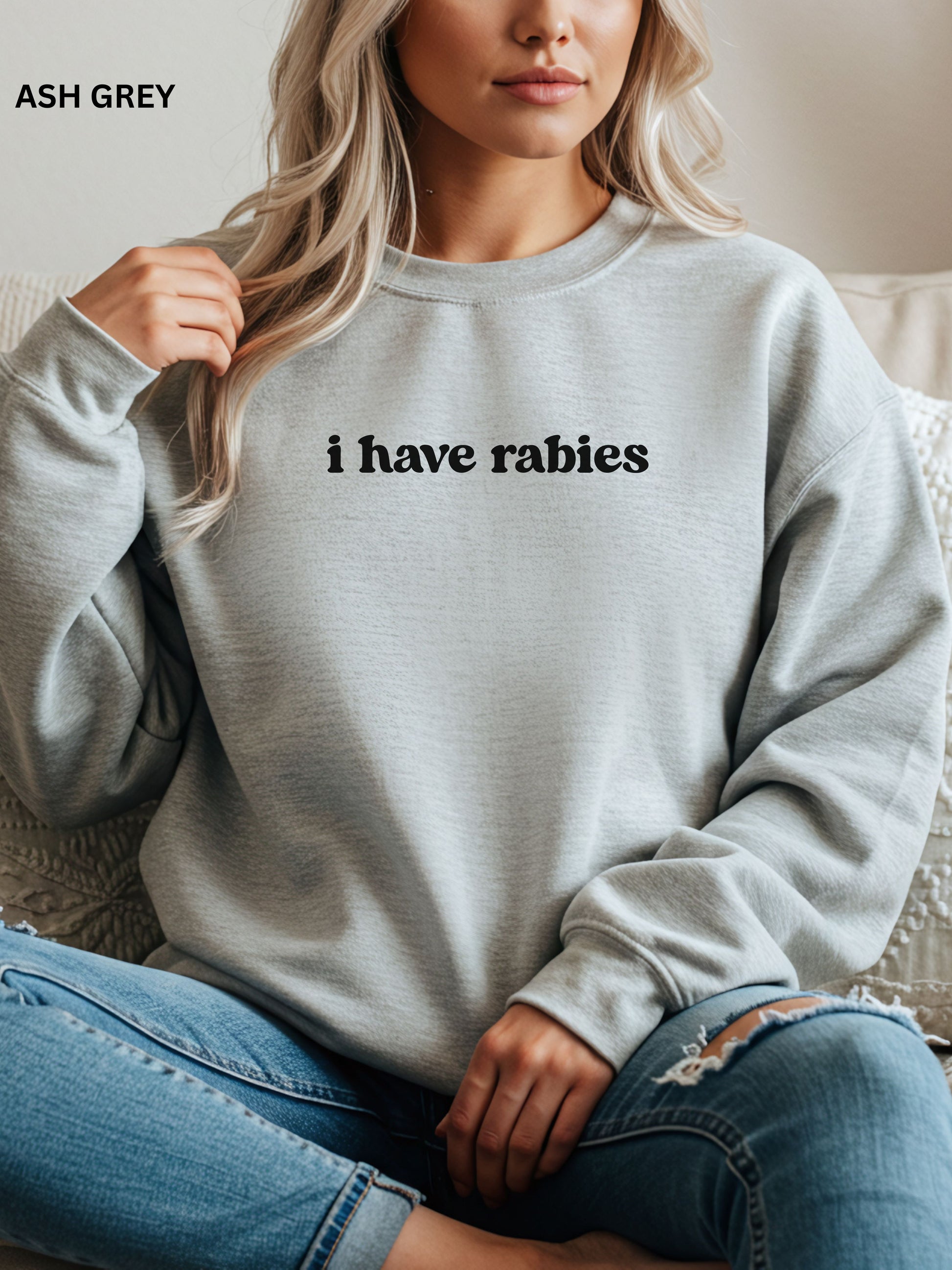 Person wearing an asg gray sweatshirt with 'i have rabies' text, sitting on a couch.