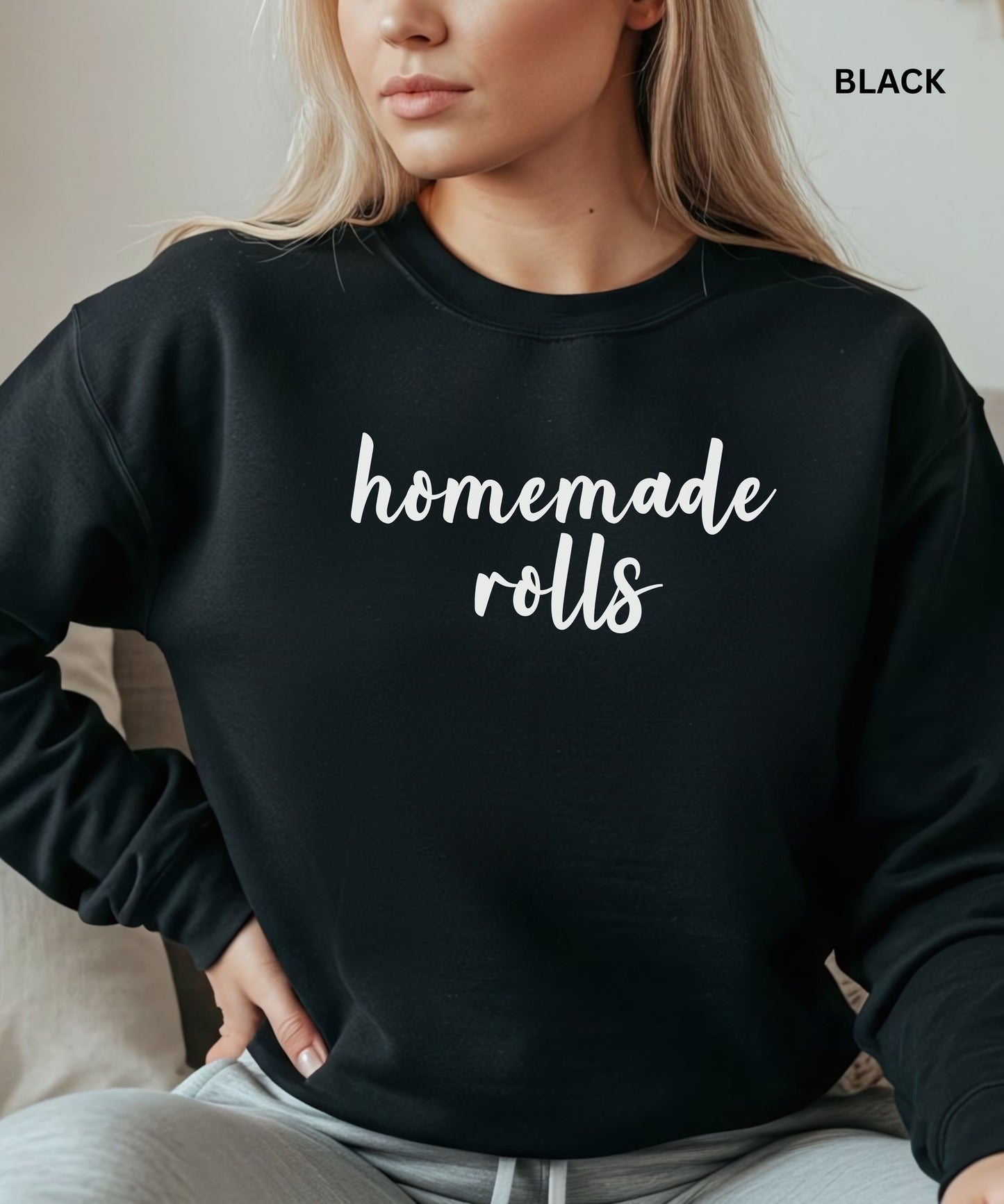 Person wearing a black sweatshirt with 'homemade rolls' text, sitting on a couch.