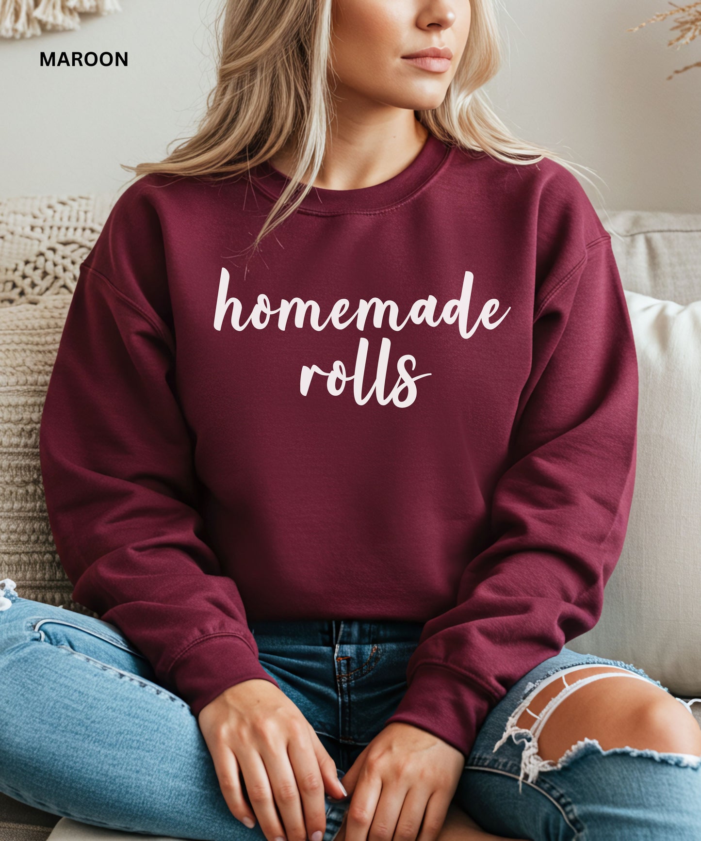 Person wearing a maroon sweatshirt with 'homemade rolls' text, sitting on a couch.
