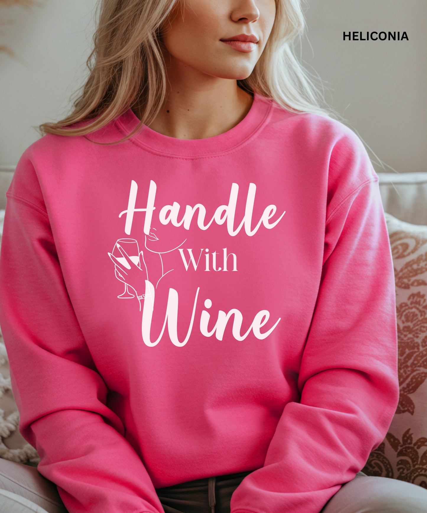 Person wearing a heliconia sweatshirt with 'Handle With Wine' text and a wine glass graphic.