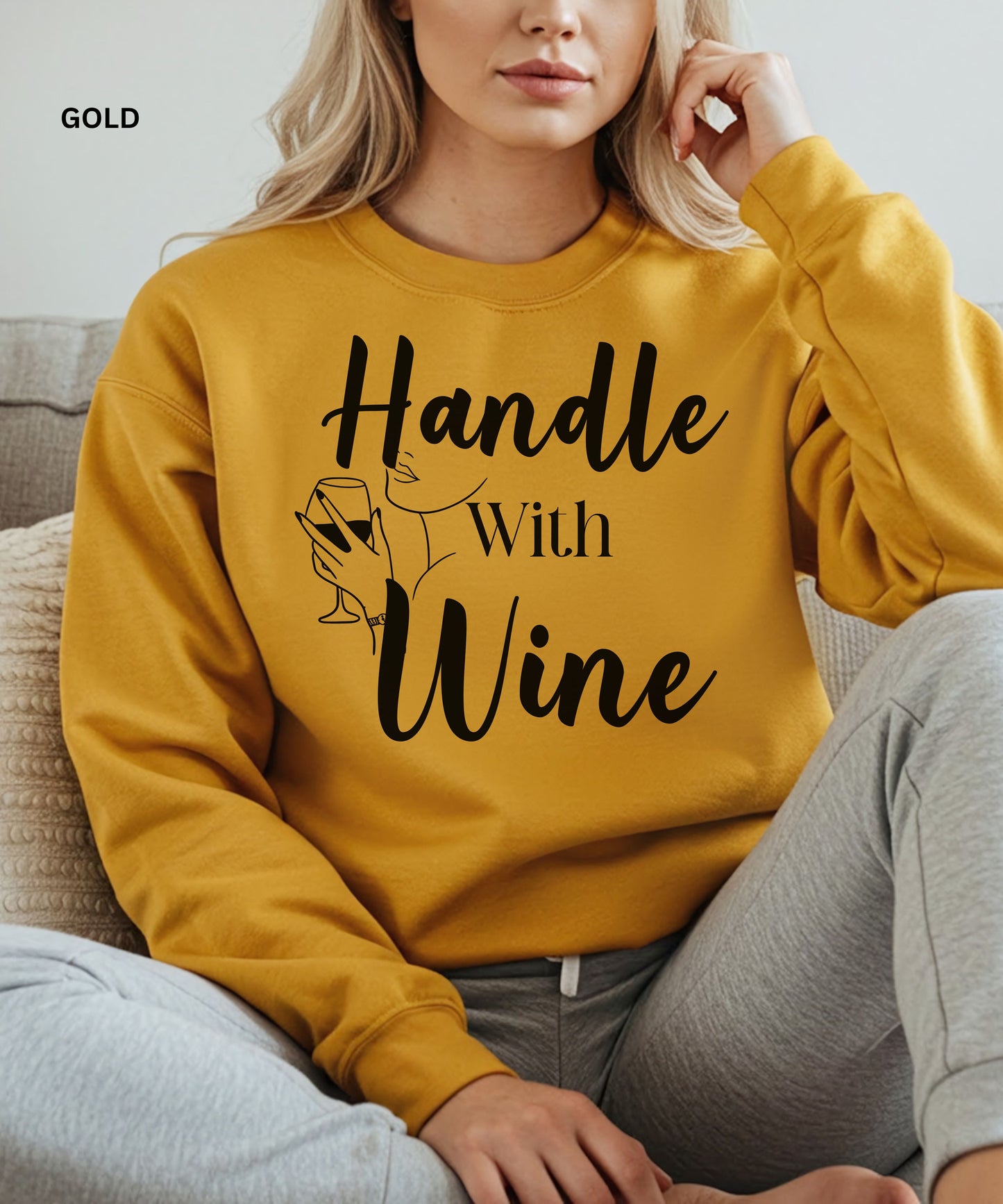 Person wearing a gold sweatshirt with 'Handle With Wine' text and graphic.