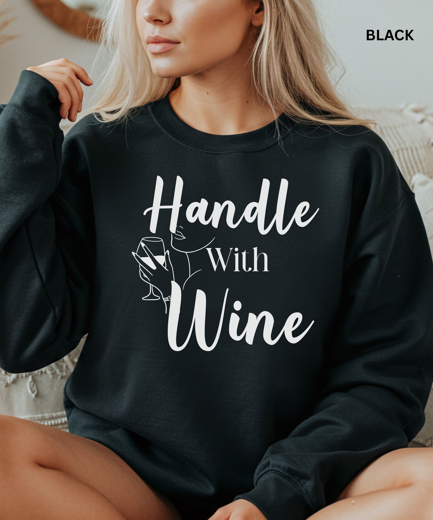 Person wearing a black sweatshirt with 'Handle With Wine' text and graphic.