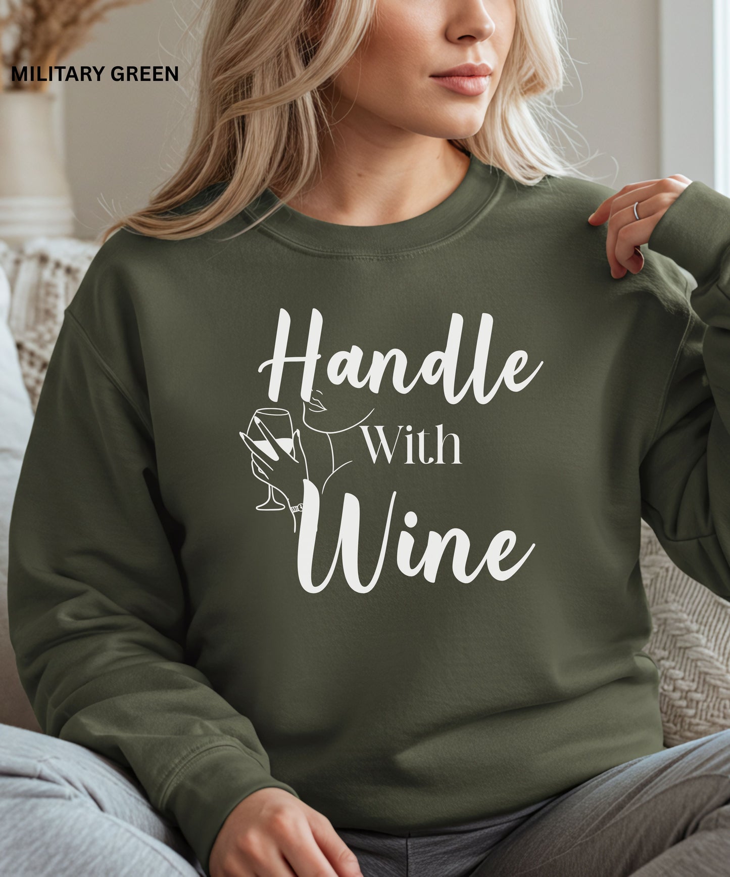 Person wearing a military green sweatshirt with 'Handle With Wine' text and graphic.