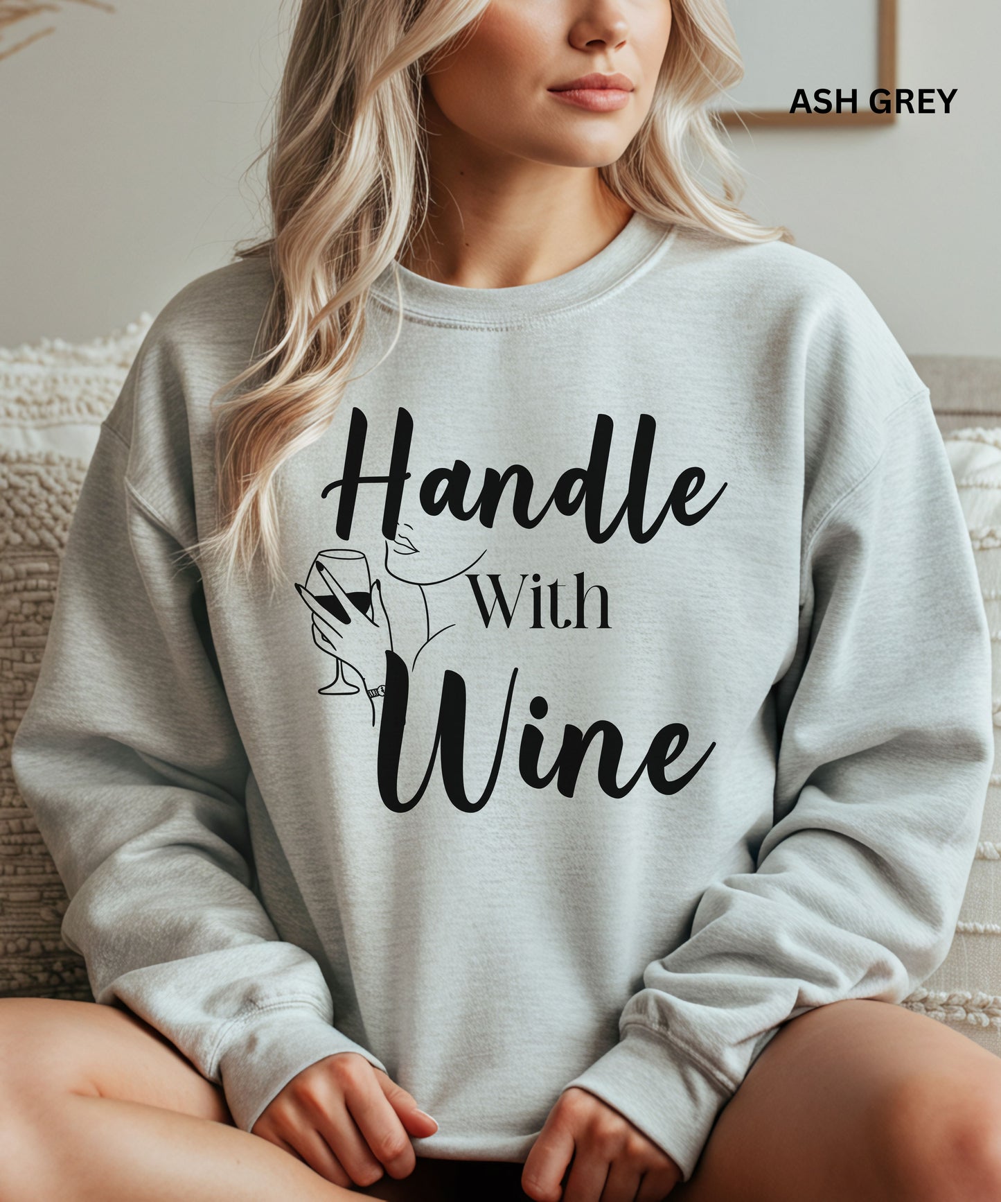 Person wearing an ash gray sweatshirt with 'Handle With Wine' text and graphic.